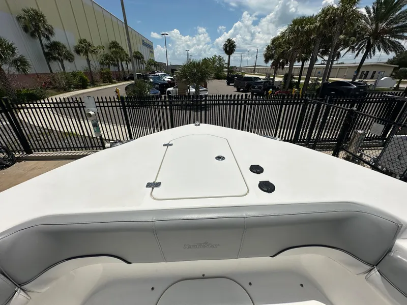 Slide: The Image of 2021 NauticStar 28XS boat bow with seating, docked near palm trees and a parking lot. - 26