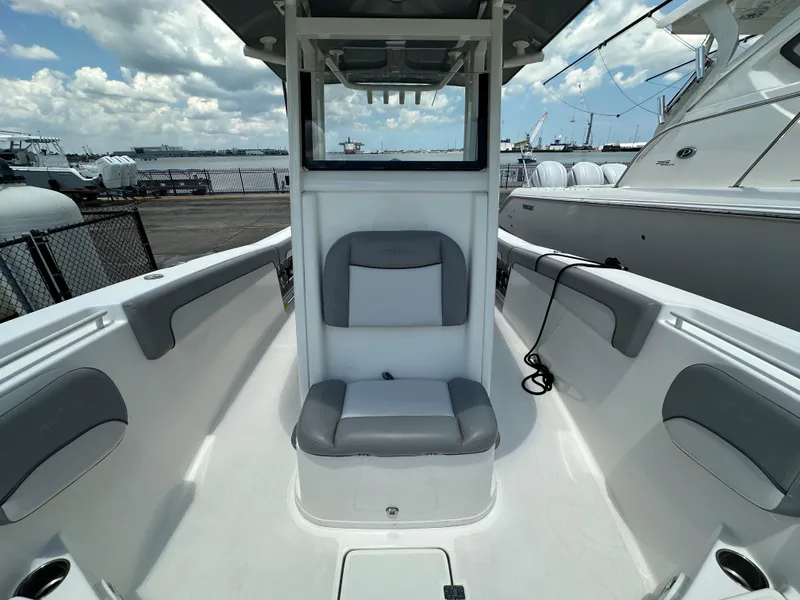 Slide: The Image of 2021 NauticStar 28XS boat interior with seating, docked at marina under cloudy sky. - 28