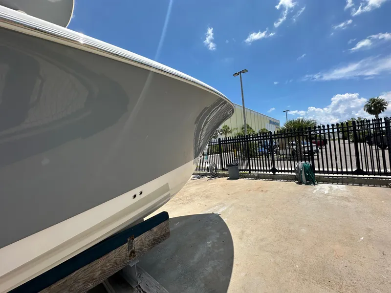 Slide: The Image of 2021 NauticStar 28XS boat in a sunny outdoor setting near a fence. - 3