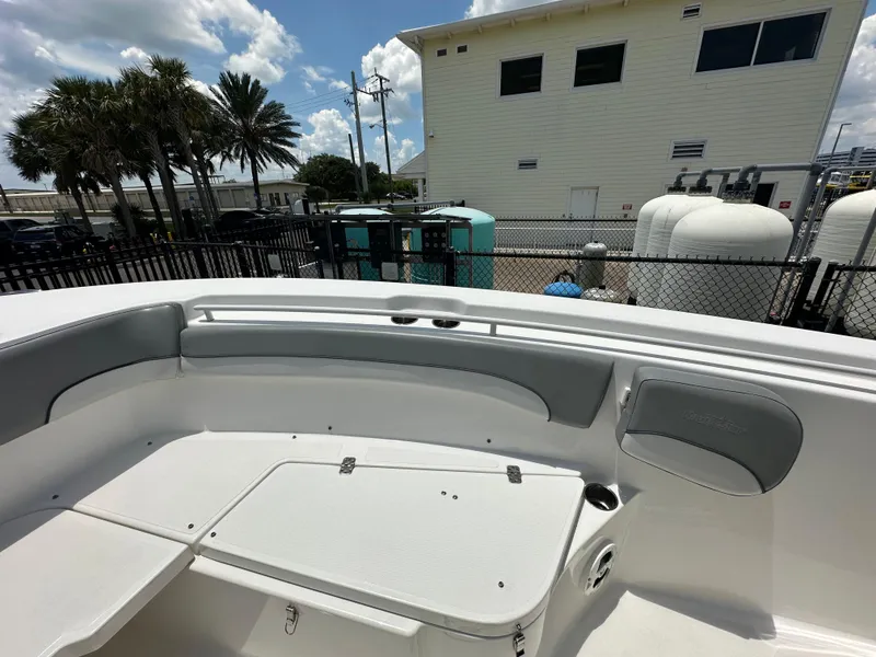Slide: The Image of 2021 NauticStar 28XS boat interior with seating, docked near a building and palm trees. - 30