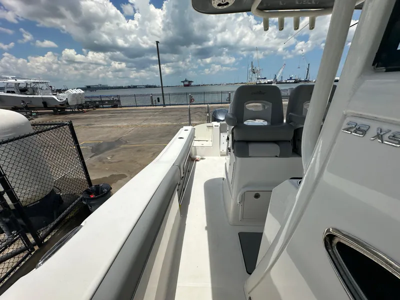 Slide: The Image of 2021 NauticStar 28XS boat docked, showcasing seating and deck under a partly cloudy sky. - 32