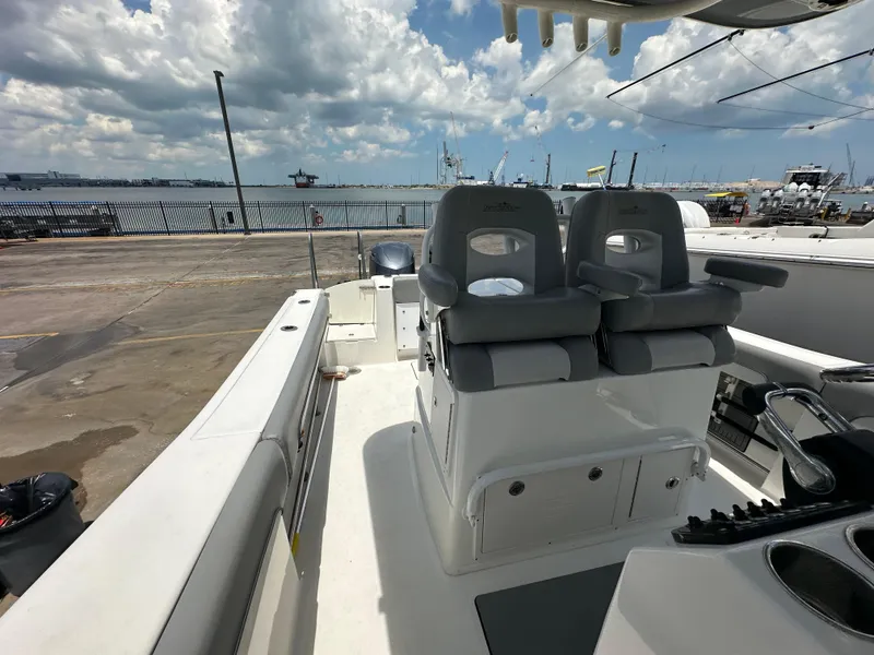 Slide: The Image of 2021 NauticStar 28XS boat interior with dual seats, docked by the waterfront. - 33