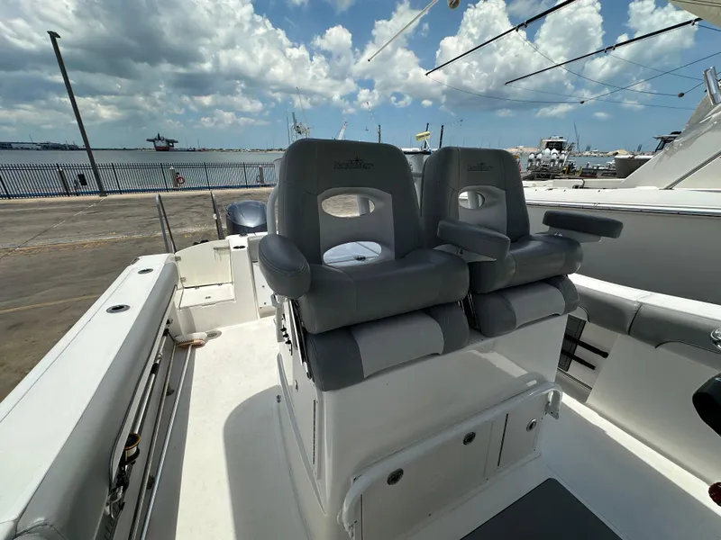 Slide: The Image of 2021 NauticStar 28XS boat interior with dual gray seats, docked under a cloudy sky. - 34