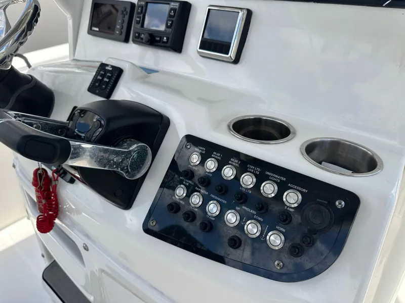 Slide: The Image of 2021 NauticStar 28XS boat console with controls, switches, and cup holders. - 37