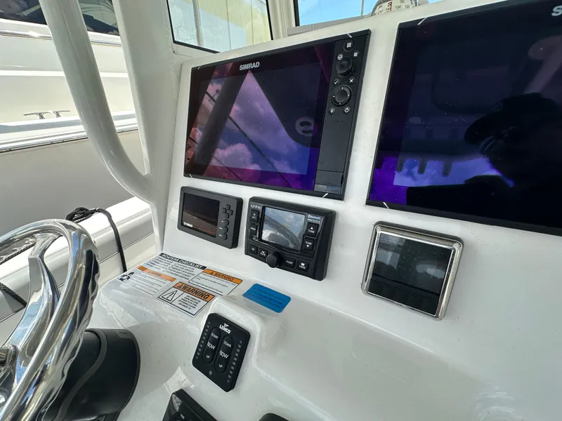Slide: The Image of 2021 NauticStar 28XS boat dashboard with Simrad displays and controls. - 39