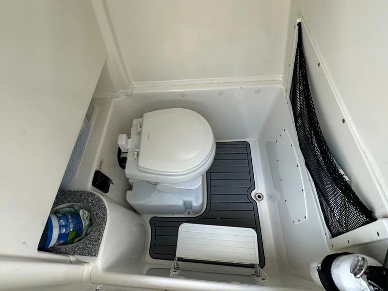 Slide: The Image of 2021 NauticStar 28XS boat interior with compact marine toilet and storage area. - 43