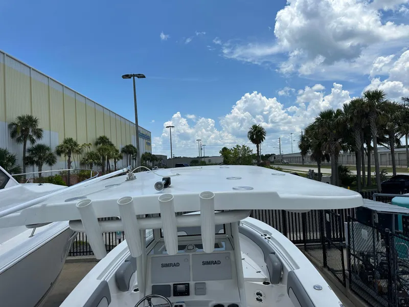 Slide: The Image of 2021 NauticStar 28XS boat with T-top, parked outdoors under a blue sky. - 48