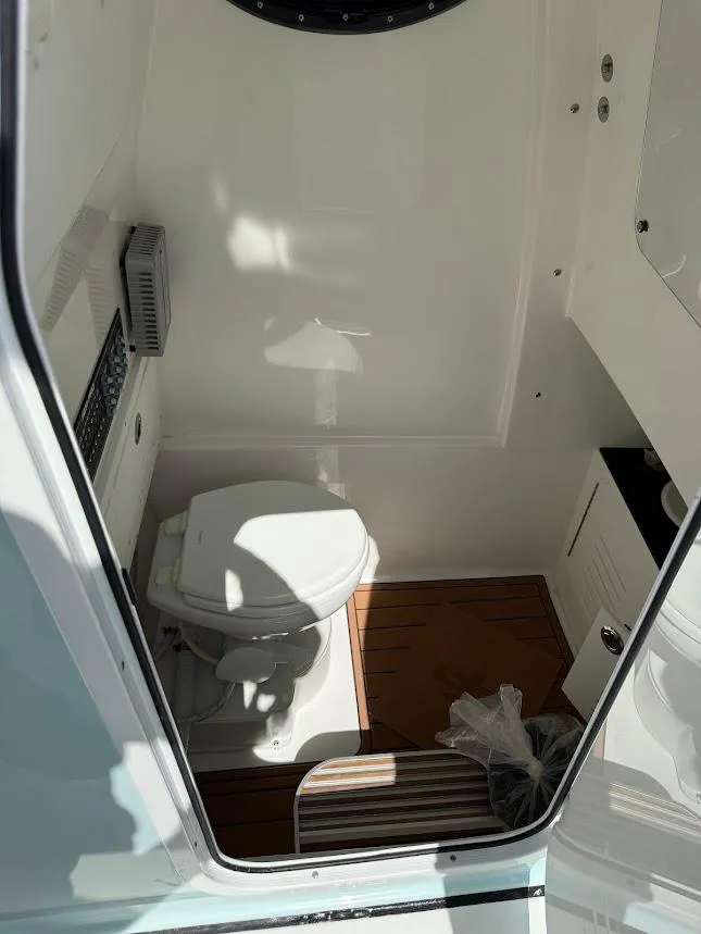 Slide: The Image of 2026 Sea Pro 292 Offshore boat interior with compact marine toilet and wooden flooring. - 22