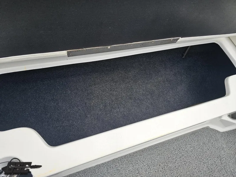 Slide: The Image of Open storage compartment in 2014 Tigé Z3 boat, featuring dark carpeted interior. - 49