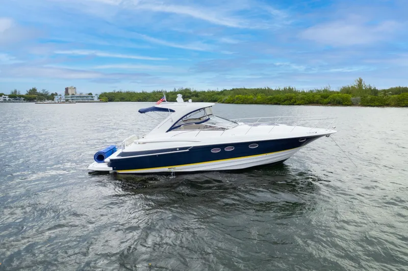 Slide: The Image of 2004 Regal 4260 Commodore yacht on calm waters with a scenic background. - 2