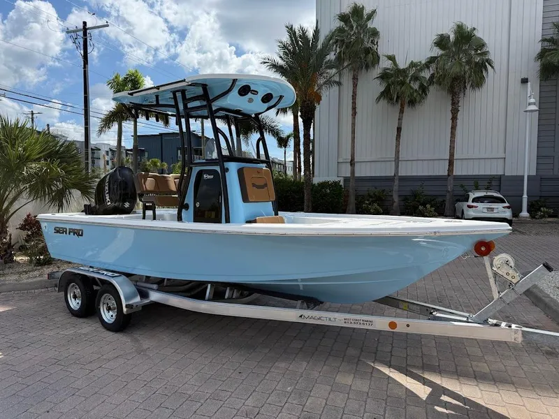 Slide: The Image of 2026 Sea Pro 210 Bay boat on trailer, parked outdoors with palm trees in background. - 1