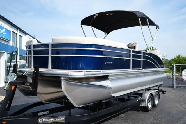The Image of 2026 Harris Cruiser 230 pontoon boat on trailer, featuring sleek blue and silver design. - 1
