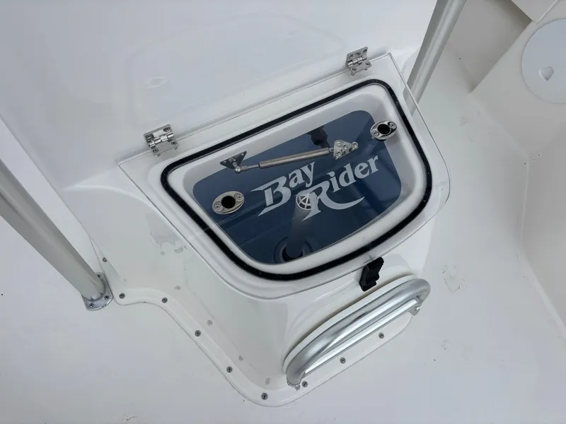 Slide: The Image of 2026 Bay Rider 239 Bay boat compartment with logo and stainless steel handle. - 24
