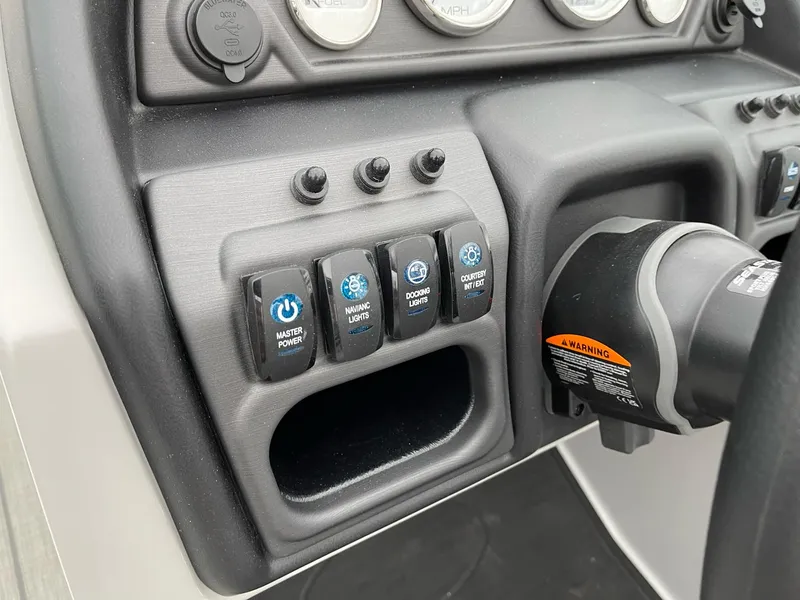 Slide: The Image of Control panel of 2025 Bentley Pontoons Legacy 243 QSB with various switches and warning label. - 15