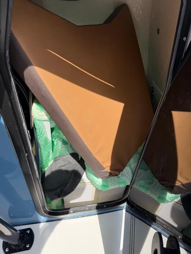 Slide: The Image of Interior view of 2026 Sea Pro 225 Sandbar boat with brown cushion and green packaging. - 12