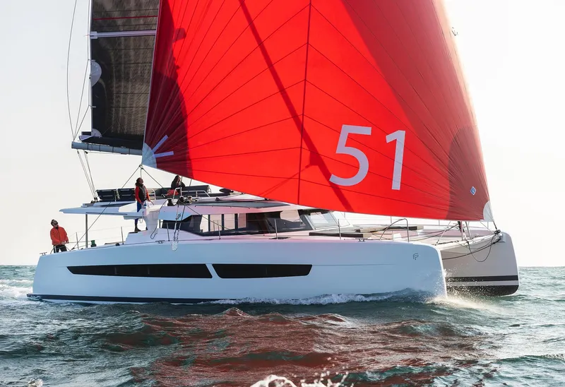Slide: The Image of 2025 Fountaine Pajot Aura 51 catamaran sailing with red sails on open water. - 3
