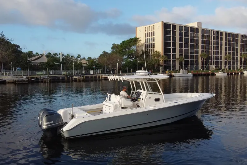 The Image of Edgewater 318CC 2013 boat on calm water near urban buildings. - 0