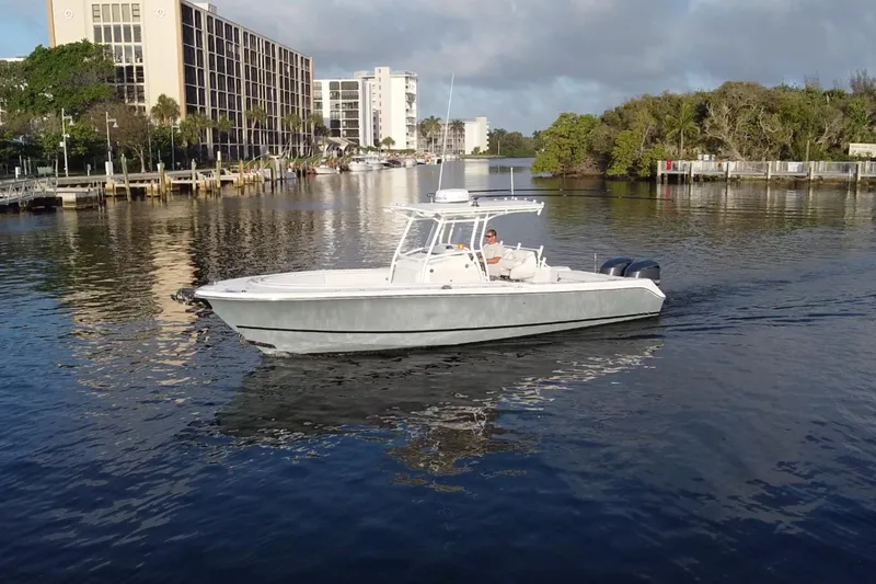 Slide: The Image of 2013 Edgewater 318CC boat cruising on a calm river near urban buildings. - 1
