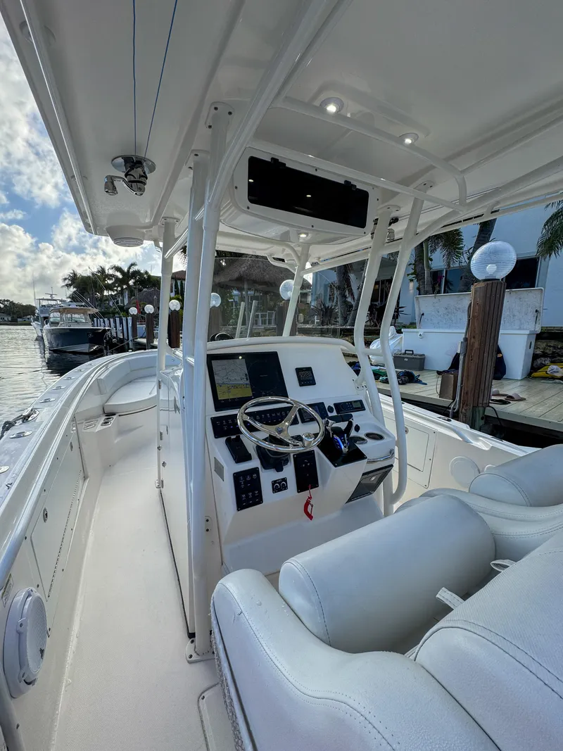 Slide: The Image of 2013 Edgewater 318CC boat interior with steering console and seating, docked by the water. - 17