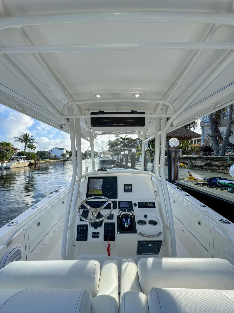 Slide: The Image of 2013 Edgewater 318CC boat interior with steering console, docked by a scenic waterfront. - 24