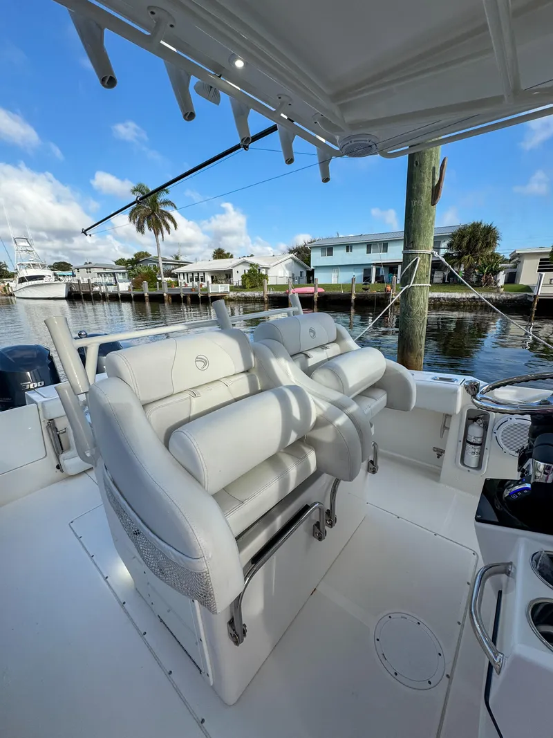 Slide: The Image of 2013 Edgewater 318CC boat interior with white seating, docked by waterfront homes. - 25