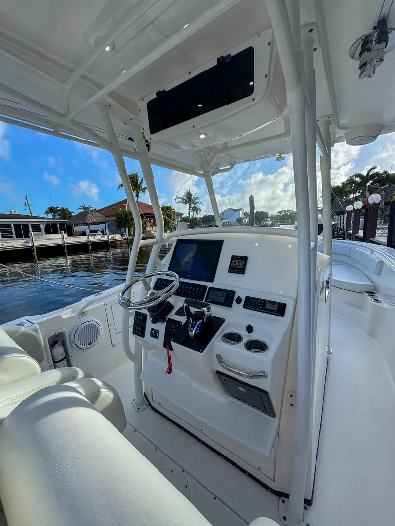 Slide: The Image of 2013 Edgewater 318CC boat cockpit with steering wheel, control panel, and seating, docked by waterfront. - 26