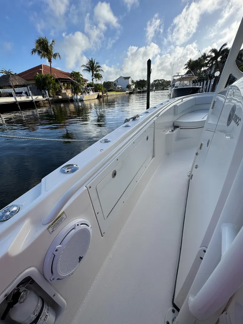 Slide: The Image of 2013 Edgewater 318CC boat docked by a scenic waterfront with palm trees. - 28