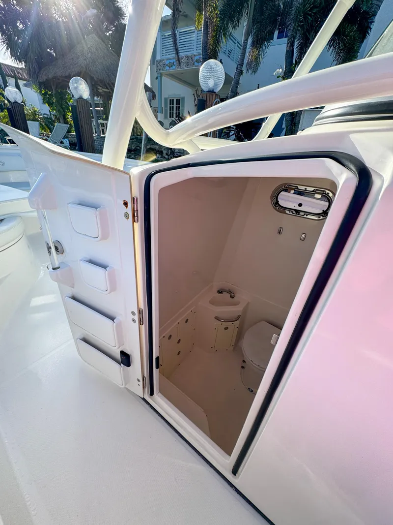 Slide: The Image of 2013 Edgewater 318CC boat interior with open door revealing compact bathroom. - 30