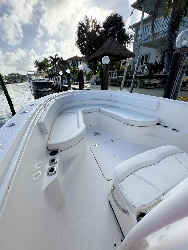 Slide: The Image of 2013 Edgewater 318CC boat with white seating, docked near waterfront homes. - 32