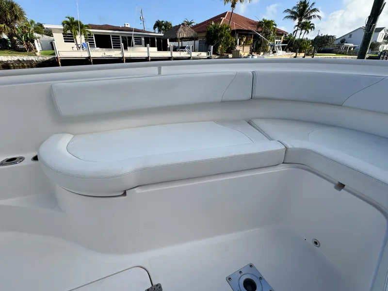 Slide: The Image of 2013 Edgewater 318CC boat interior with white cushioned seating, dockside view. - 37