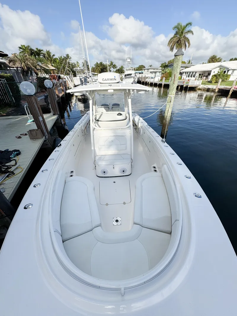 Slide: The Image of 2013 Edgewater 318CC boat docked in a marina, clear sky, palm trees. - 46