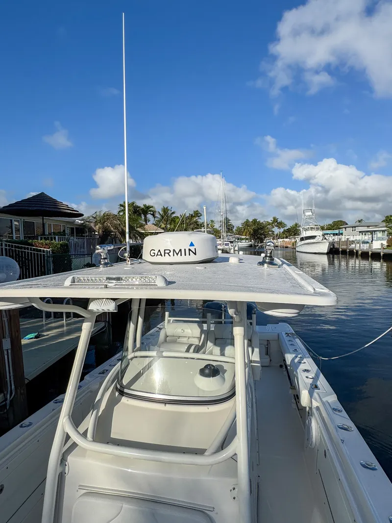 Slide: The Image of 2013 Edgewater 318CC boat docked, featuring Garmin equipment, under a clear blue sky. - 48