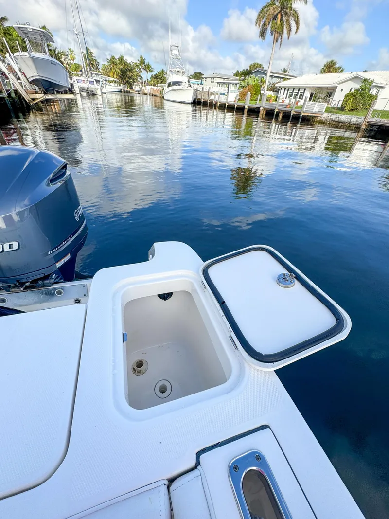Slide: The Image of 2013 Edgewater 318CC boat with open storage compartment, docked by calm waters. - 8