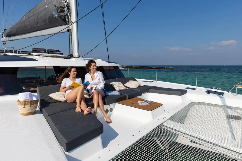 The Image of 2025 Fountaine Pajot Aura 51 catamaran with two women relaxing on deck. - 0