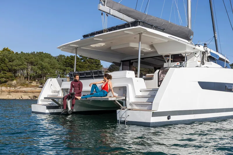 Slide: The Image of 2025 Fountaine Pajot Aura 51 catamaran with people relaxing on the deck. - 9