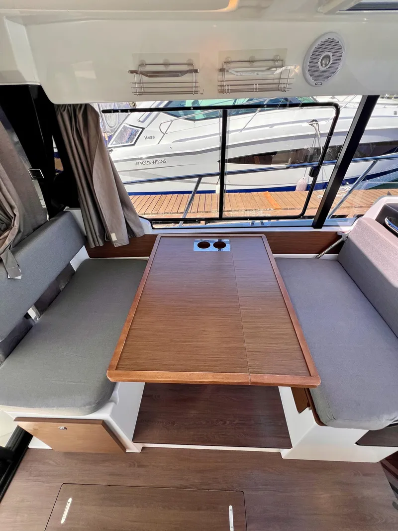 Slide: The Image of Interior of 2019 Jeanneau NC 1095 boat with wooden table and gray seating. - 11