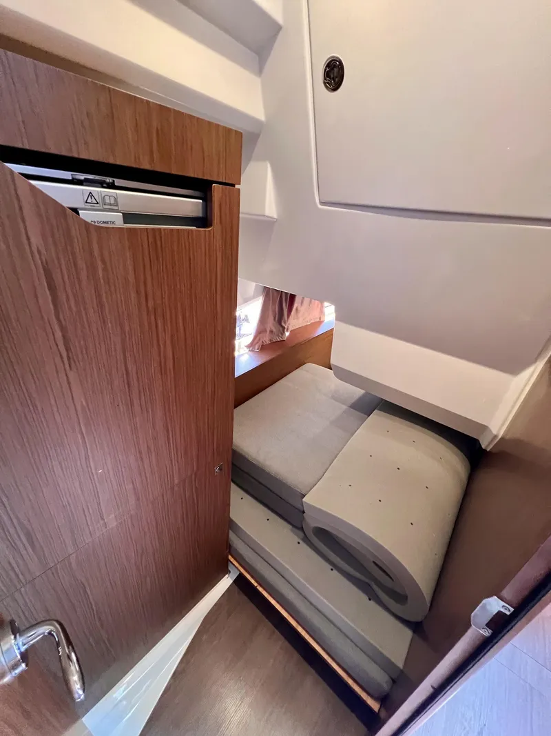 Slide: The Image of 2019 Jeanneau NC 1095 cabin interior with folded cushions and wooden door. - 14