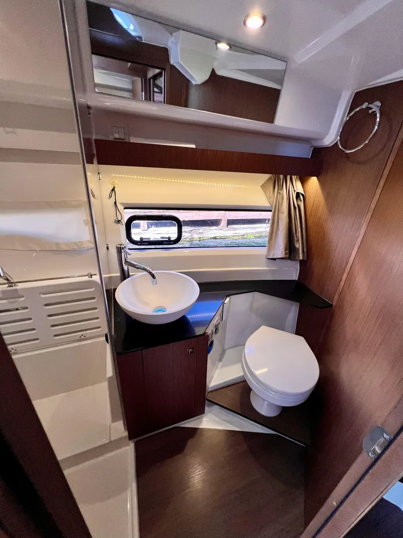 Slide: The Image of 2019 Jeanneau NC 1095 boat bathroom with modern sink, toilet, and wood accents. - 16
