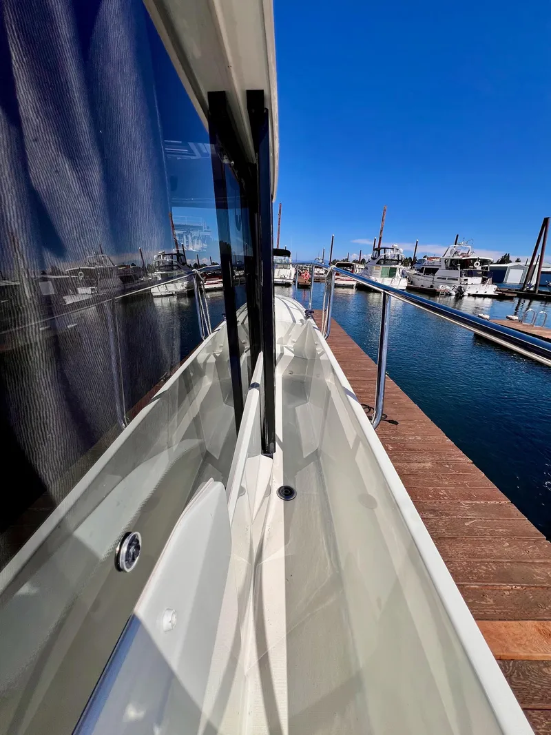 Slide: The Image of 2019 Jeanneau NC 1095 docked at marina under clear blue sky. - 5