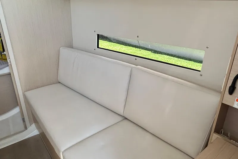Slide: The Image of Interior of 2021 Beneteau Oceanis 30.1 yacht with beige seating and window view. - 21