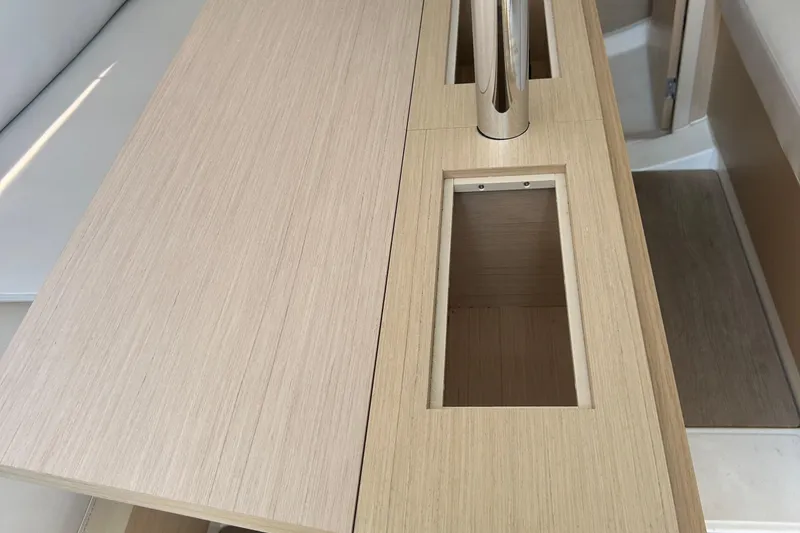 Slide: The Image of Interior of 2021 Beneteau Oceanis 30.1 yacht, featuring wooden table with storage compartments. - 31