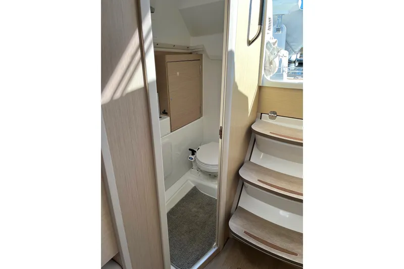 Slide: The Image of Interior of 2021 Beneteau Oceanis 30.1 yacht, featuring compact bathroom and wooden steps. - 34