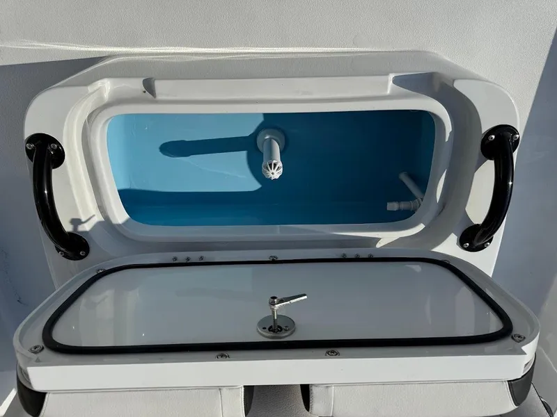 Slide: The Image of Open storage compartment on 2025 Shallow Sport 18 Sport boat, featuring a blue interior. - 18