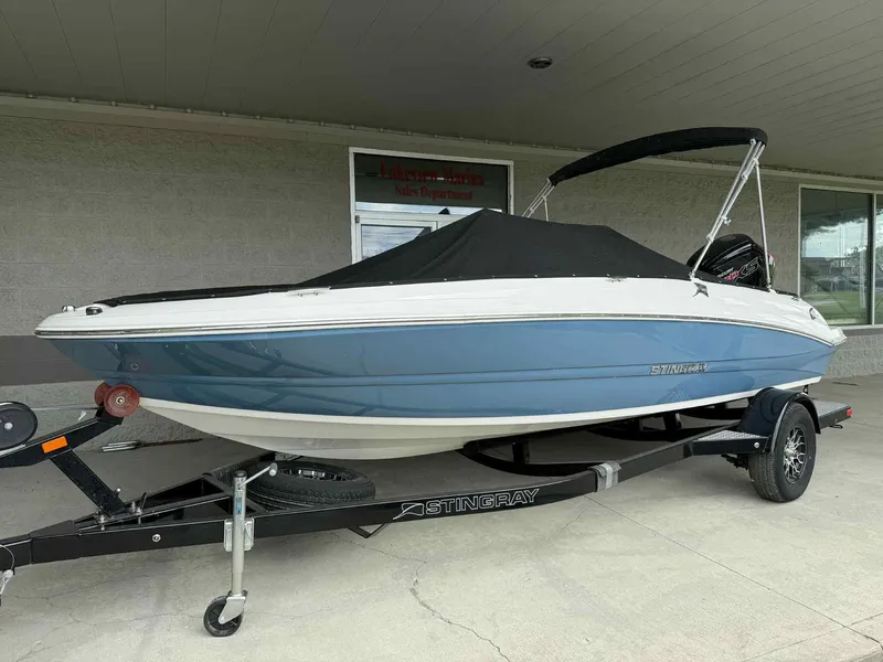 The Image of 2024 Stingray 182 SC boat on trailer, covered and parked outside a building. - 0