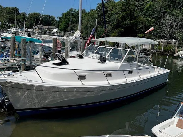 The Image of 2003 Mainship Pilot 34 boat docked in a marina, surrounded by other vessels. - 1