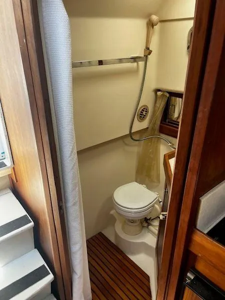 Slide: The Image of 2003 Mainship Pilot 34 bathroom with shower, toilet, and wooden floor accents. - 16