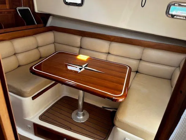Slide: The Image of 2003 Mainship Pilot 34 interior with beige seating and wooden table. - 18