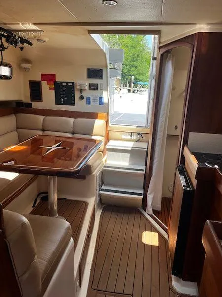 Slide: The Image of 2003 Mainship Pilot 34 interior with dining area, wooden flooring, and natural light. - 25