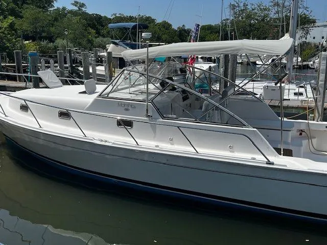 Slide: The Image of 2003 Mainship Pilot 34 boat docked in a marina, featuring a sleek white design. - 3