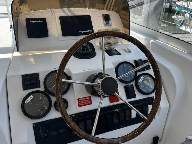 Slide: The Image of 2003 Mainship Pilot 34 helm with Raymarine electronics and classic wooden steering wheel. - 9